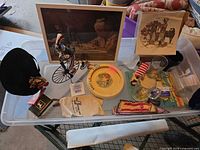 overview of entire lot on tray showing figurine, prints, plate, hat, glassware, ephemera