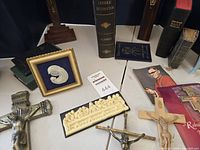 tabletop view showing crucifixes, books, cameo, plaque, holy cards