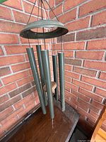Wind chime hanging against brick wall showing tubes, canopy, clapper, sail