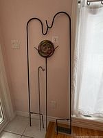 Full view of blown glass disc on stake with two tall shepherd hooks and small hook