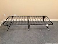 Full view of unfolded IKEA SYLLING folding bed frame showing spring base and legs