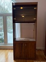 Full frontal view of tall wood veneer cabinet showing three sections