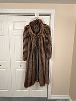 Front view of full-length raccoon fur coat hanging