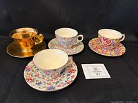 All four teacup and saucer sets displayed on black cloth