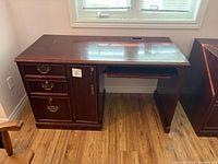 Front view of dark wood desk showing drawers, CPU door, keyboard tray