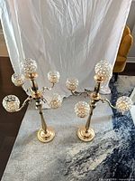 Two matching gold-tone floor candelabras standing side by side