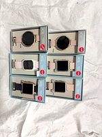 Front view of six boxed TCK watches showing assorted face shapes and pink straps