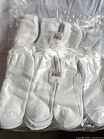 Overall view of two factory-sealed packs of white crew socks