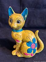 Front view of mustard yellow ceramic cat coin bank with floral painting