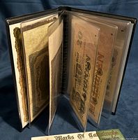 Open folio showing multiple banknotes in clear sleeves