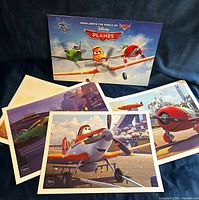 All four lithographs fanned with presentation folder displayed upright