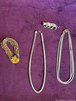 All four jewelry items laid out on purple background