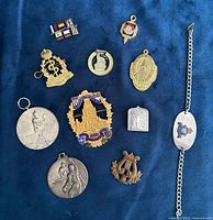 Full lot overview showing all pins, medals, bracelet and badges on blue background