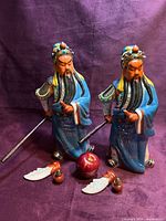Front view of both porcelain Guan Yu figures with accessories for scale