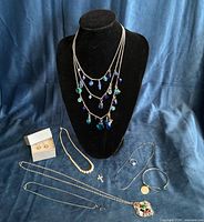Full lot on fabric backdrop with bust displaying blue bead necklace, remaining items laid out
