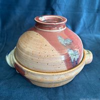 Full view of lidded clay pot showing glazing pattern and side handles