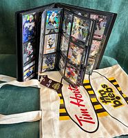 Binder standing open displaying card pages next to TimBiebs tote bag