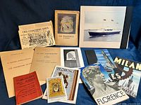 Group shot of all booklets, brochures, phrase book, art card and mounted photograph on blue background