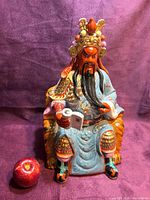 Full frontal view of Guan Yu figurine with apple for scale