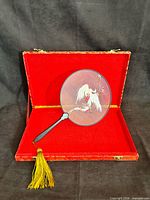 Fan inside open red velvet-lined case