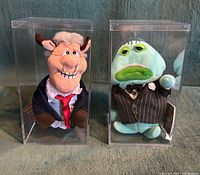 Both Meanies plush toys inside their acrylic boxes