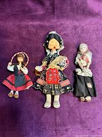 Front view of three cloth dolls on purple background