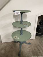 Full view of three-tier painted pedestal table showing overall design, color, and ball-and-claw feet