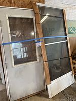 Both doors leaning against wall: shed door left, screen door right