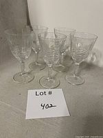Five matching wine glasses on surface showing overall lot