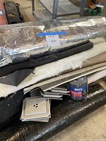 Overall lot with foil insulation roll, fiberglass batt, corner bead, drain grates, Henry can visible