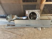 overview of duct elbow, round collar with damper, rectangular sheet, rods against wire mesh