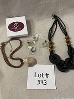 All items in the lot: four rings in plastic sleeves, shell pendant bead necklace, wood bead necklace, jewelry box visible