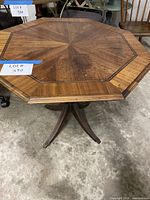 Top and base of octagonal wood occasional table, showing inlaid design and brass-capped legs