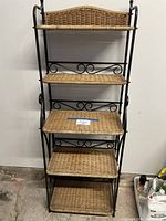 Full view of bakers rack showing wrought iron frame and five wicker shelves