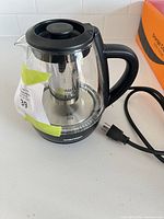 Front view showing glass body, stainless steel infuser, Chefman logo and power cord