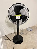 Front view of black Honeywell pedestal fan showing blade guard, control panel, and base