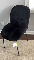 Front angled view of one black velvet chair on metal legs