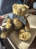 Front view of brown plush teddy bear with checkered bow