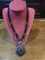 Full view of necklace on stand showing cord, pendant and toggle