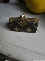 Front view of monogram coin purse showing clasp and exterior pattern