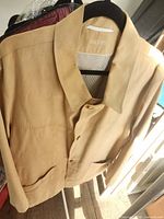Front view of tan suede Bugatti blazer on hanger showing buttons and pockets