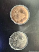 Front view of both medals in capsules, showing finishes