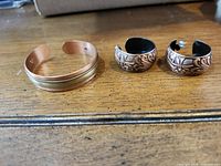 Cuff bracelet and both earrings displayed on table
