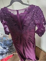 Back view of purple gown showing lace, sequins, sheer upper back, ruched waist, full-length skirt