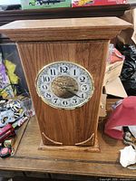 Front view of oak mantel clock showing analog dial and wood finish