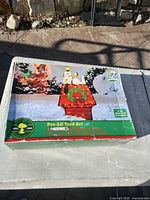 Front of box showing image of assembled Snoopy doghouse decoration