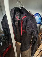 Front view of Westbeach black snowboard jacket on hanger, showing zipper and logo