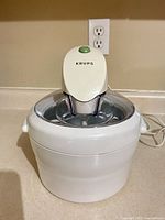 Front view of Krups white ice cream maker showing motor housing, bowl, cord