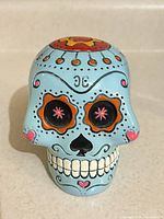 Front view of light blue sugar skull coin bank showing face details