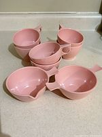 Stacked pink Melmac cups with milk and sugar dishes